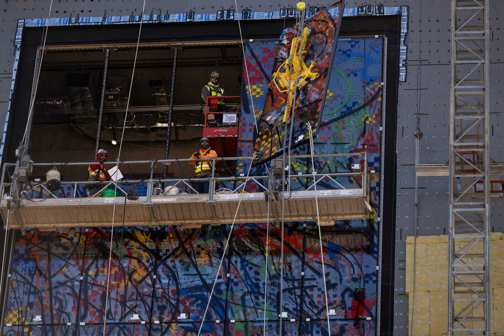 Crews work to install one of 35 stained glass panels for "Uprising of the Sun."