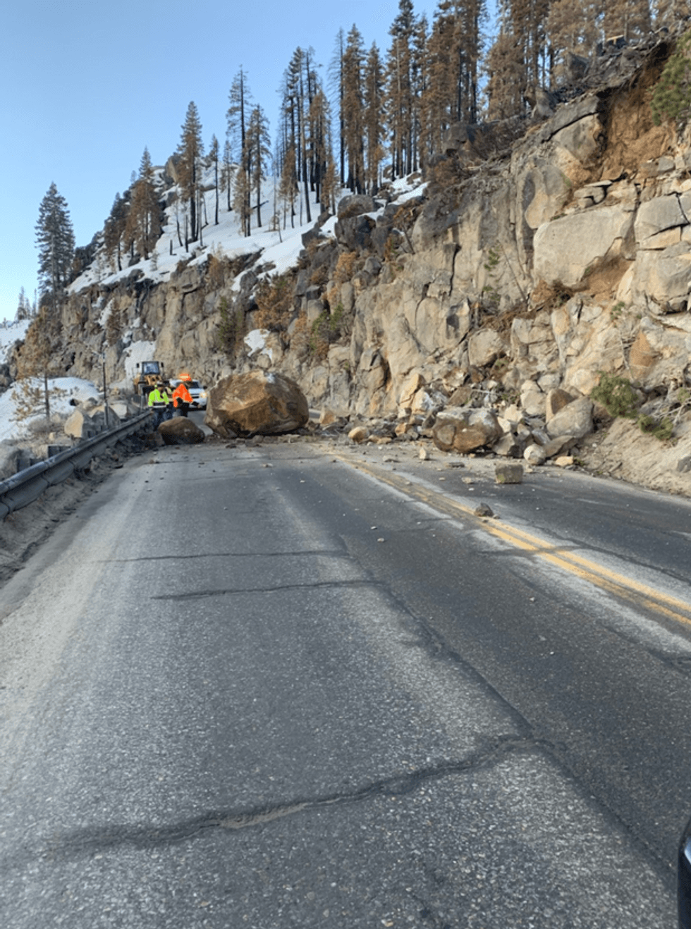 Crews works to clear a boulder on the roadway at Echo Summit.