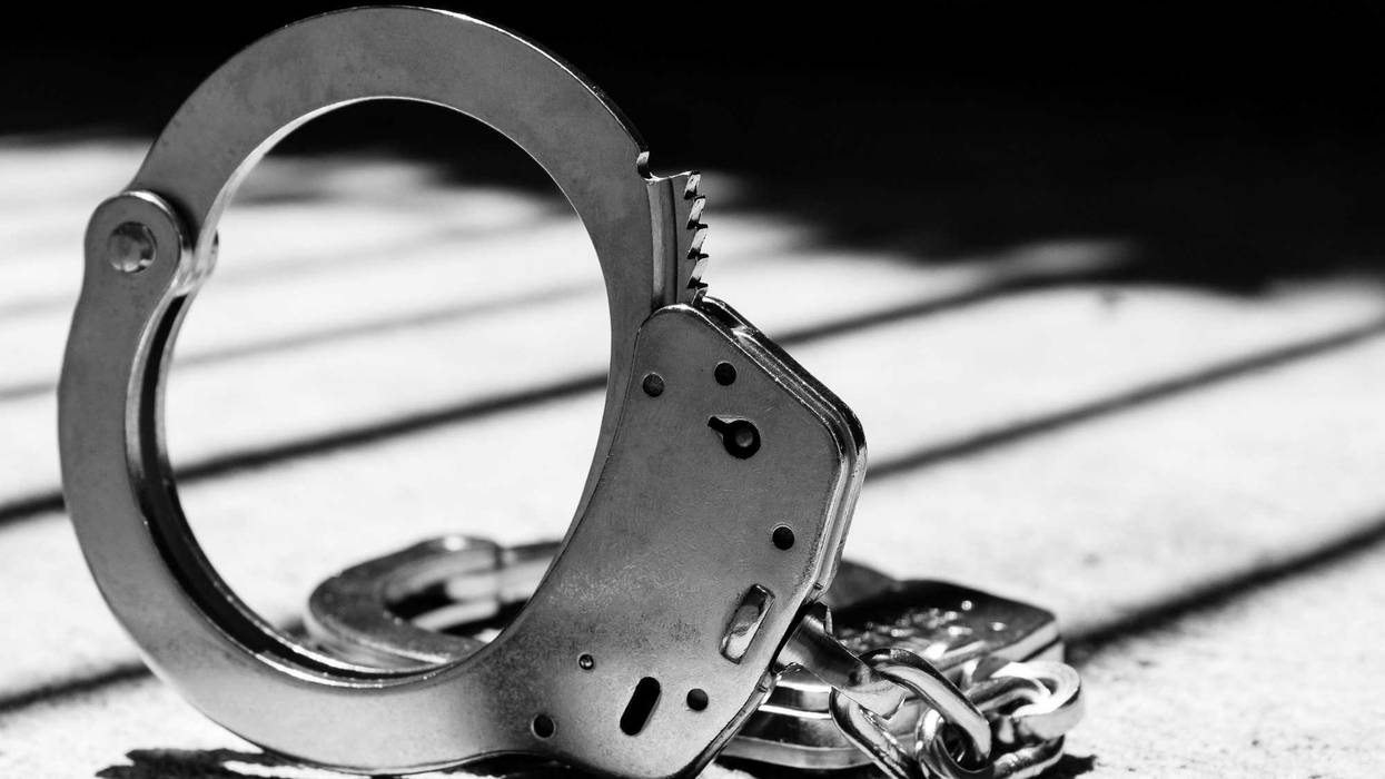 Criminal Handcuff with Bars Behind in Shadows