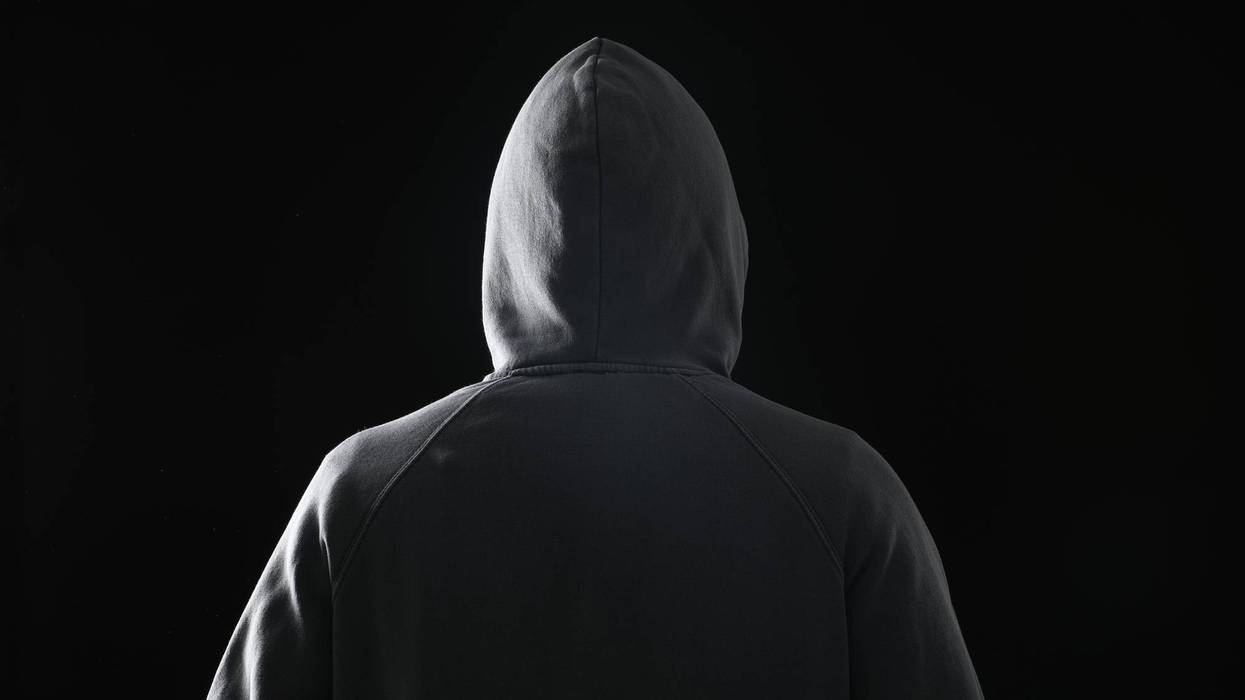 Criminal in hood on dark background, back view