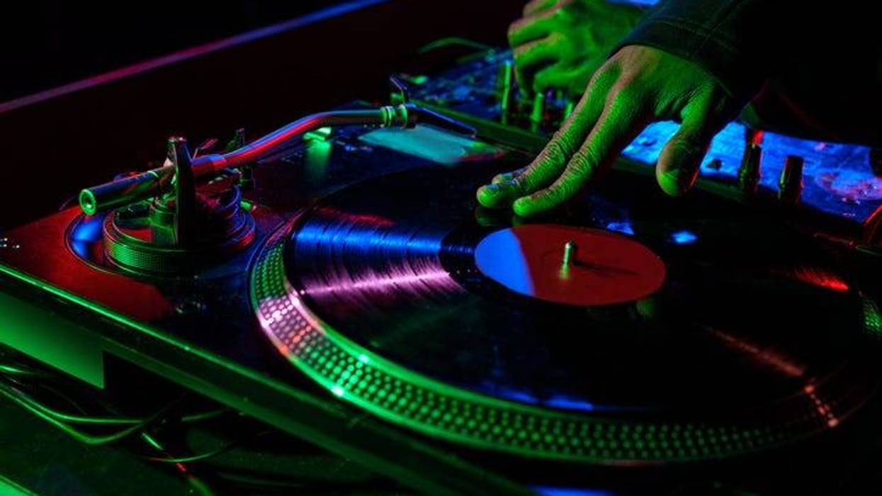 cropped view of DJ hands with sound mixer and vinyl in nightclub