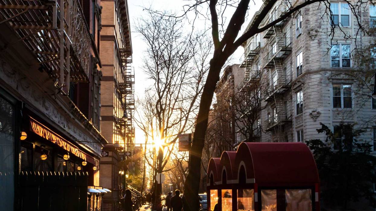 Crowd of people at a restaurant with outdoor dining tables on Perry Street in the West Village neighborhood of New York City with sunlight background