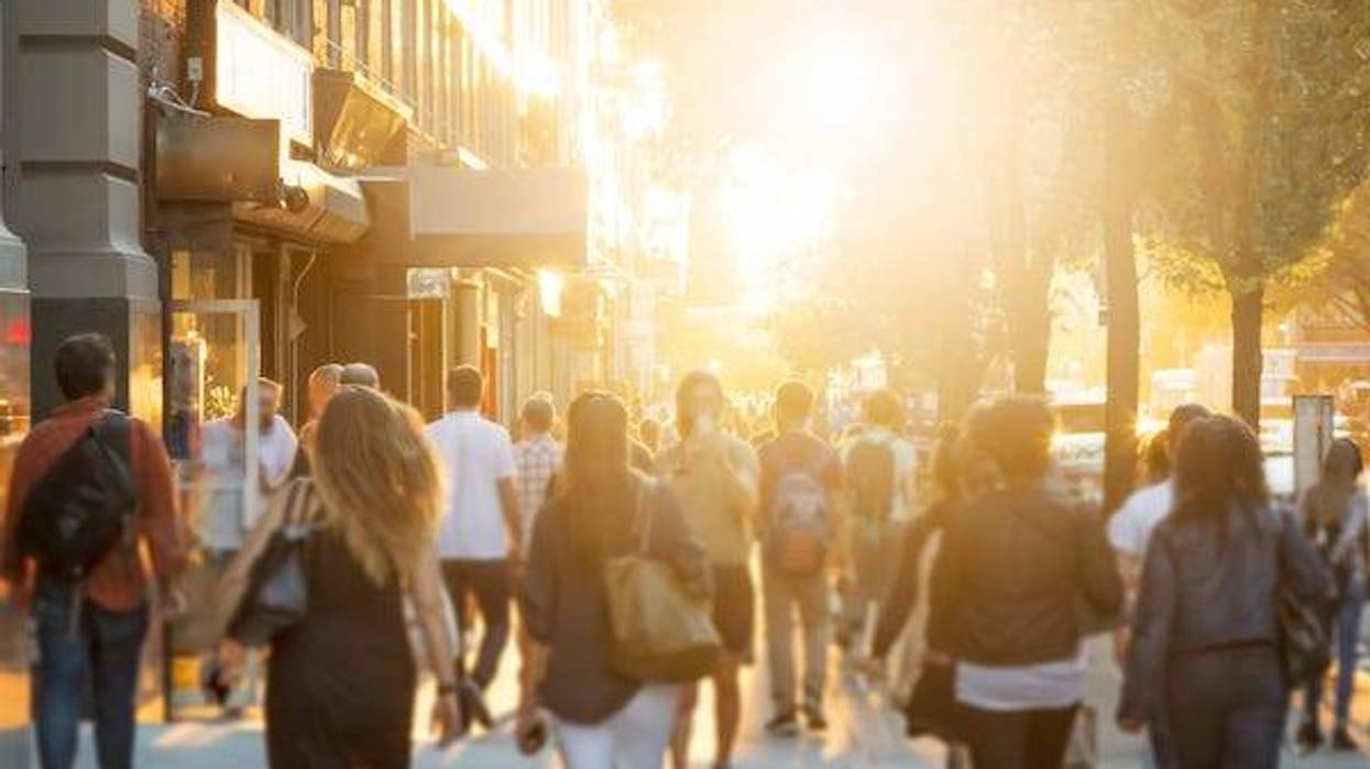 Crowd of people walking in a city during sunrise