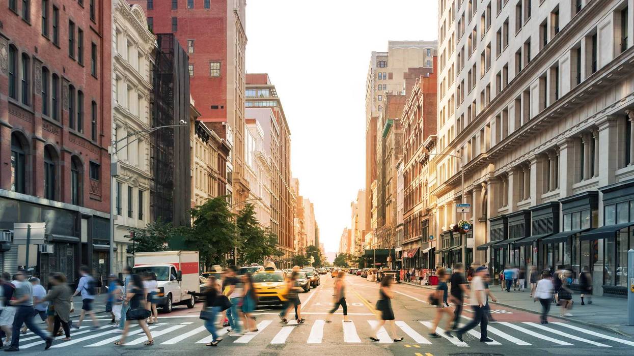 Crowds of people walking across a busy crosswalk at the intersection of 23rd Street and 5th Avenue in Manhattan New York City.