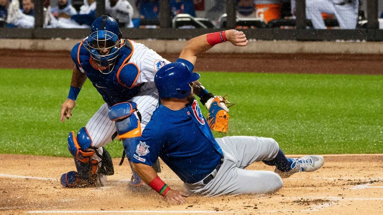 Cubs left fielder Kyle Schwarber (12) slides under the tag by Mets catcher Wilson Ramos (40) and scores a run.