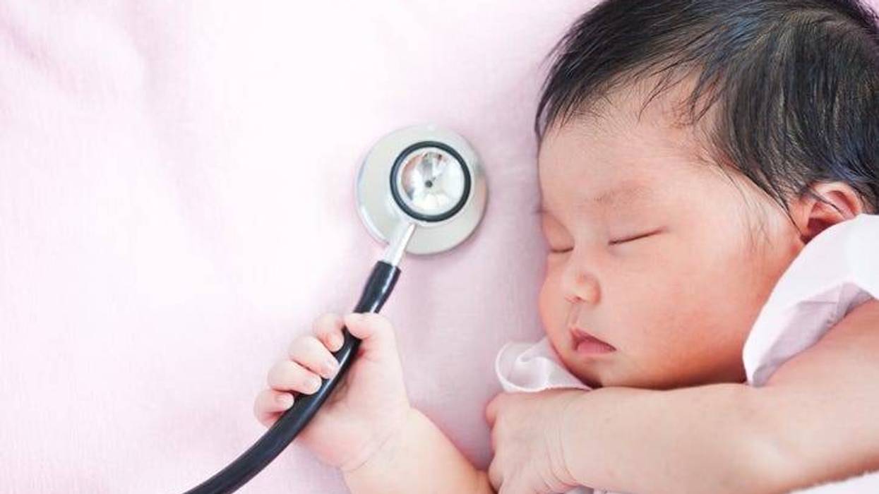 Cute asian newborn baby girl sleeping and holding medical stethoscope in hand