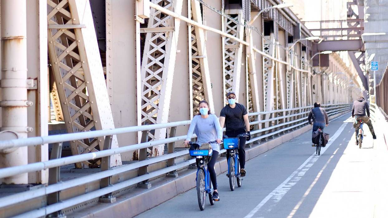 Cyclists wearing masks ride on the Queensboro Bridge as the coronavirus continues to spread across the United States on on May 13, 2020 in New York City.