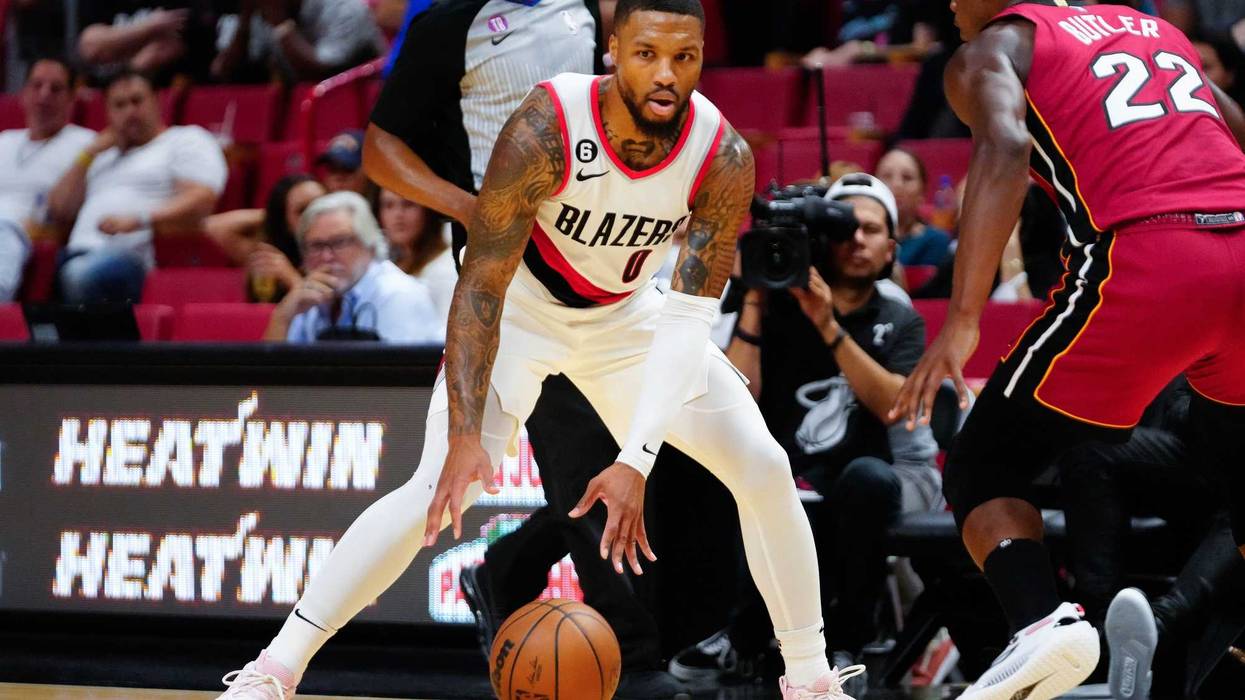 Damian Lillard dribbles the ball around Jimmy Butler