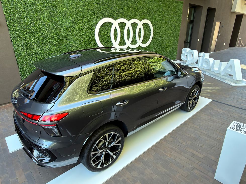 Dark grey Audi SUV on display with white Audi rings logo on a green wall.
