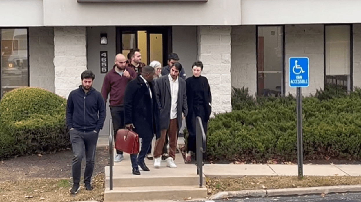 Defendant Mirvan Dinler (brown pants) talks with his attorney Shaka Johnson (maroon valise) as they leave the District Court building in Radnor Township on Thursday.
