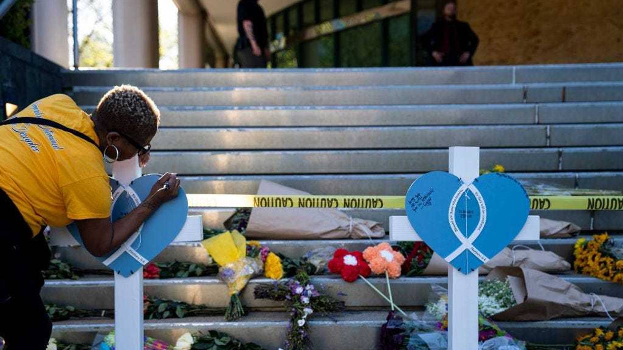 Deindra Bailey writes a message on a cross at the Old National Bank on April 11, 2023 in Louisville, Kentucky.
