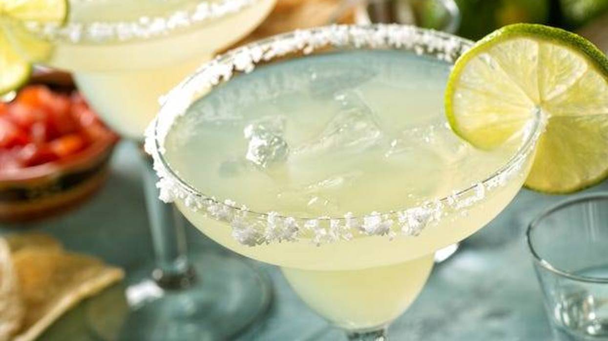 Delicious tequila and lime margaritas on an outdoor table with tortilla chips and pico de gallo