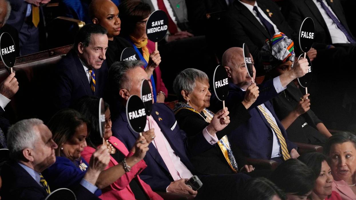 Democratic members of congress hold protest signs as President Trump addresses a joint session of Congress at the U.S. Capitol