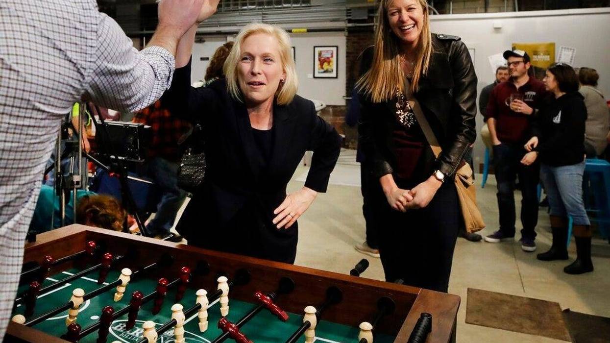 Democratic presidential candidate Sen. Kirsten Gillibrand, D-N.Y., high-fives a foosball opponent as partner Casey Leach of Manchester, N.H., laughs at a campaign meet-and-greet, Friday, March 15, 2019, at To Share Brewing in Manchester, N.H