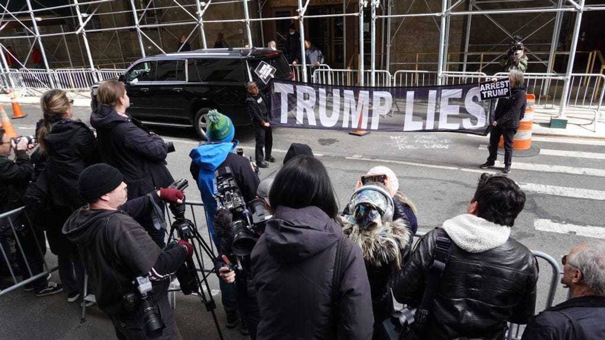 Demonstrators hold a banner in front a group of journalists outside of the Criminal Courts Building on March 22, 2023 in New York City.