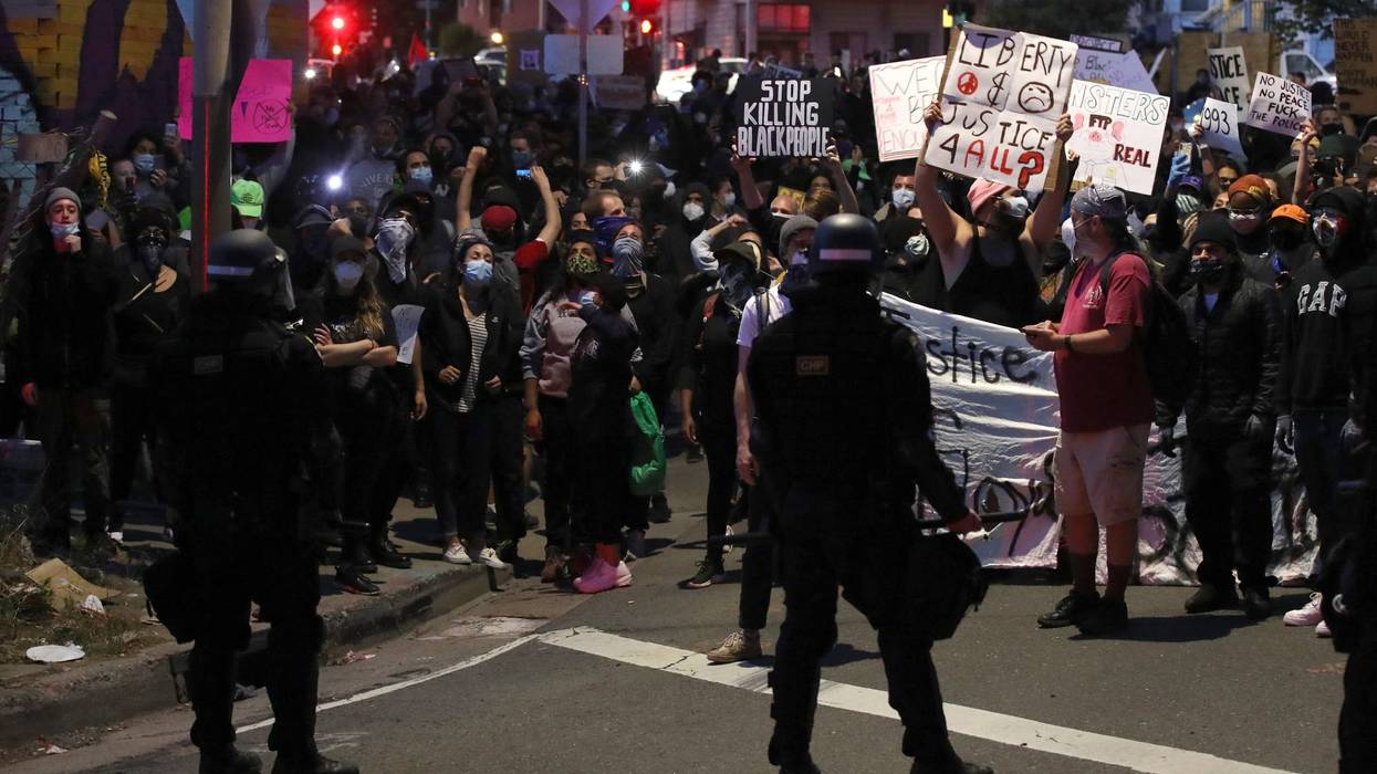 Demonstrators hold signs in front of California Highway Patrol officers during a protest sparked by the death of George Floyd while in police custody on May 29, 2020 in Oakland, California.
