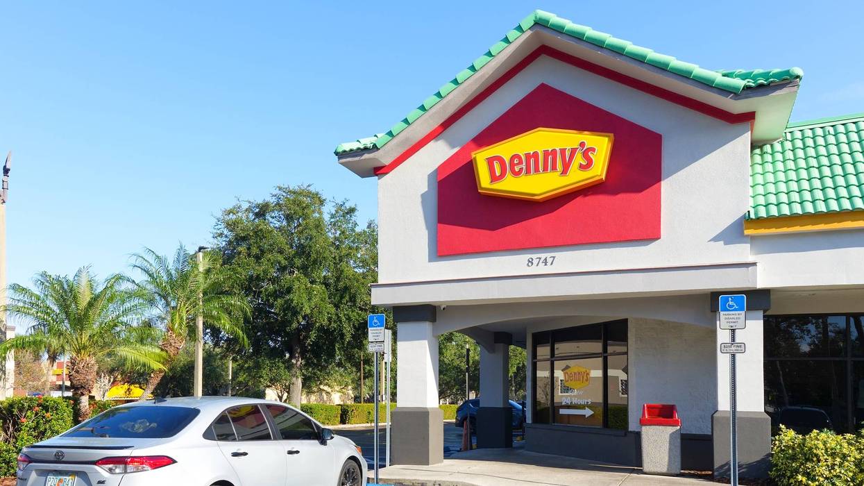Denny's restaurant exterior with iconic logo, palm trees, and clear blue sky in a sunny location