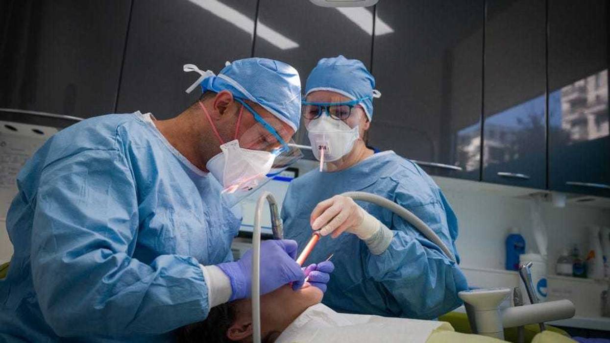Dentist Fiez Mughal (L) and Dental Nurse Johanna Bartha (R) carry out a procedure on a patient in one of the six surgery rooms at East Village dental practice on May 28, 2020 in London, England.