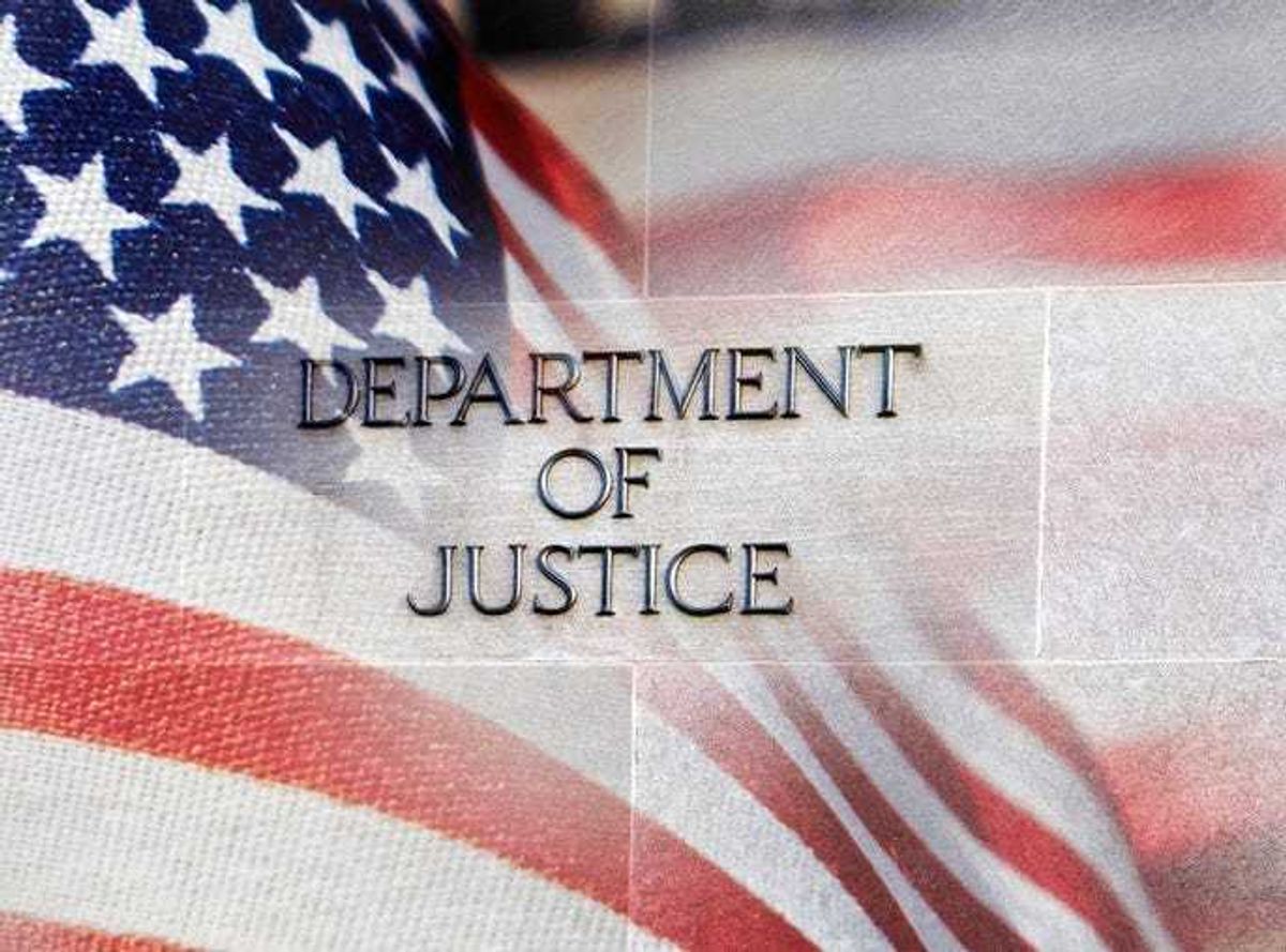 Department of Justice building sign with an American flag behind it