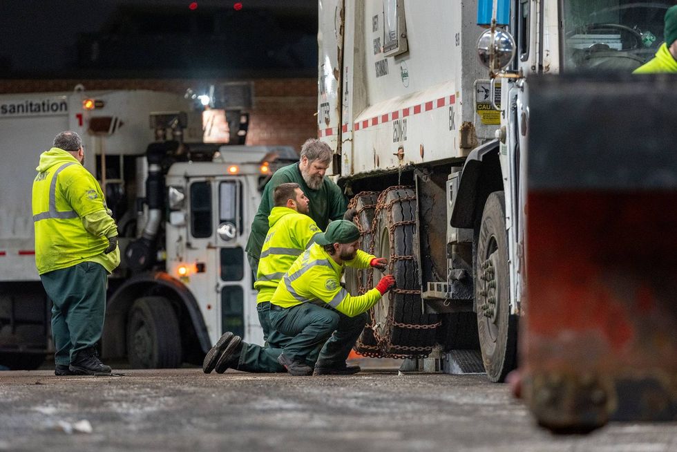 Department of Sanitation workers outfit garbage trucks with tire chains ahead of the snow storm, in the Brooklyn borough on Feb. 21