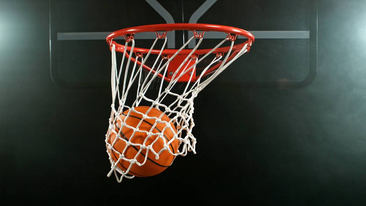 Detail of basketball ball hitting the hoop, top view. Isolated on black background.