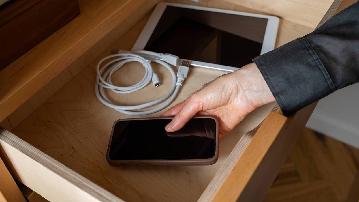 Digital detox from gadgets, social media, device addiction and mobile technology control with woman hands putting phone into furniture drawer.