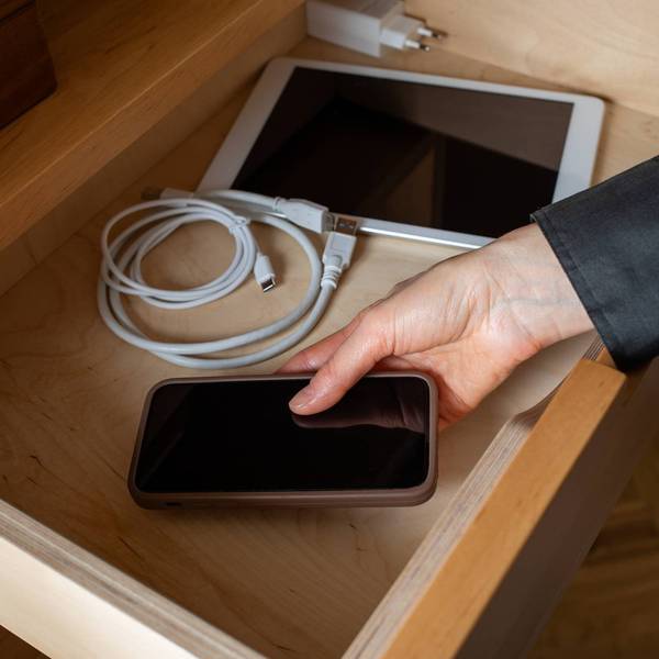 Digital detox from gadgets, social media, device addiction and mobile technology control with woman hands putting phone into furniture drawer.