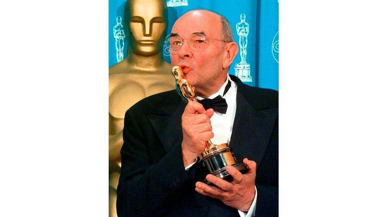 director Stanley Donen kisses the Oscar he received for Lifetime Achievement backstage at the 70th Academy Awards