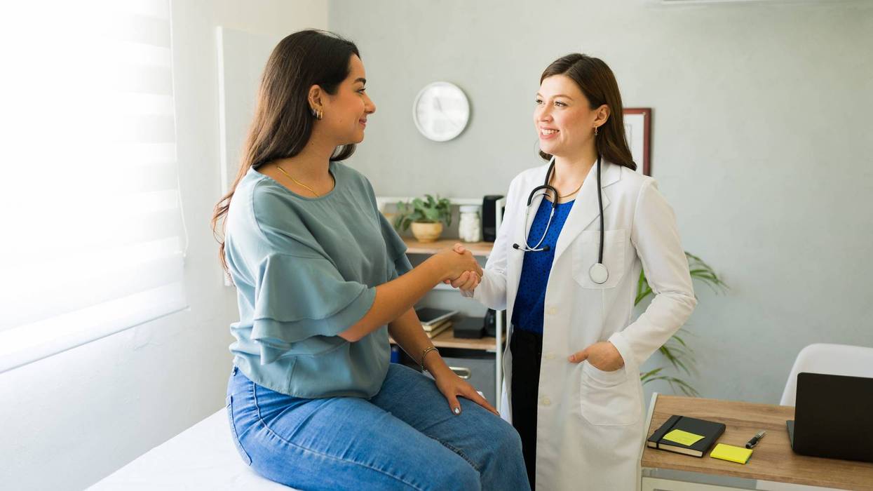 Doctor happily shaking hands with her patient after a successful consultation in her office.