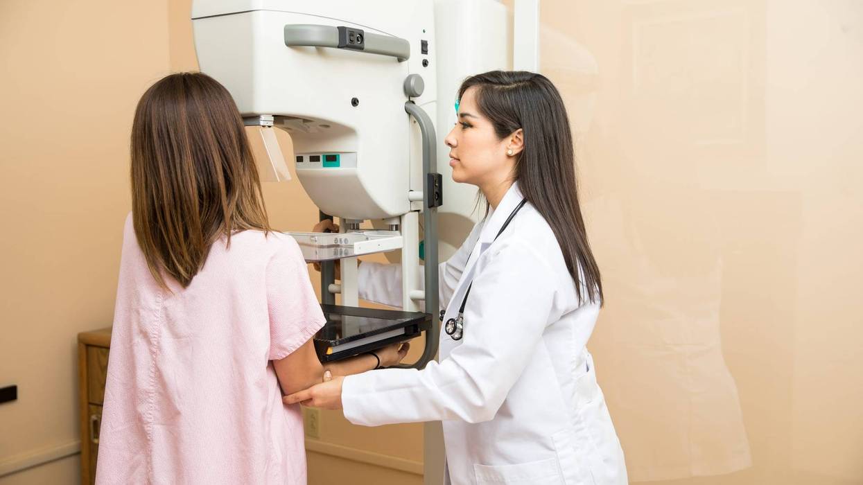 Doctor helping patient get a mammogram - stock photo