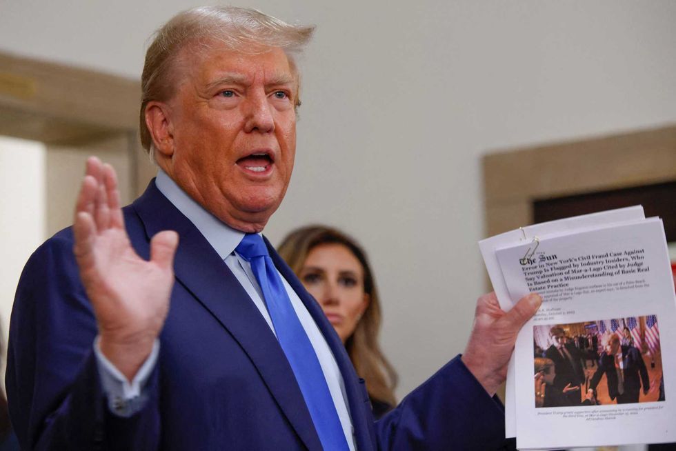 Donald Trump displays a media article outside the court room at the New York State Supreme Court on the first day of his civil fraud trial Oct. 2, 2023