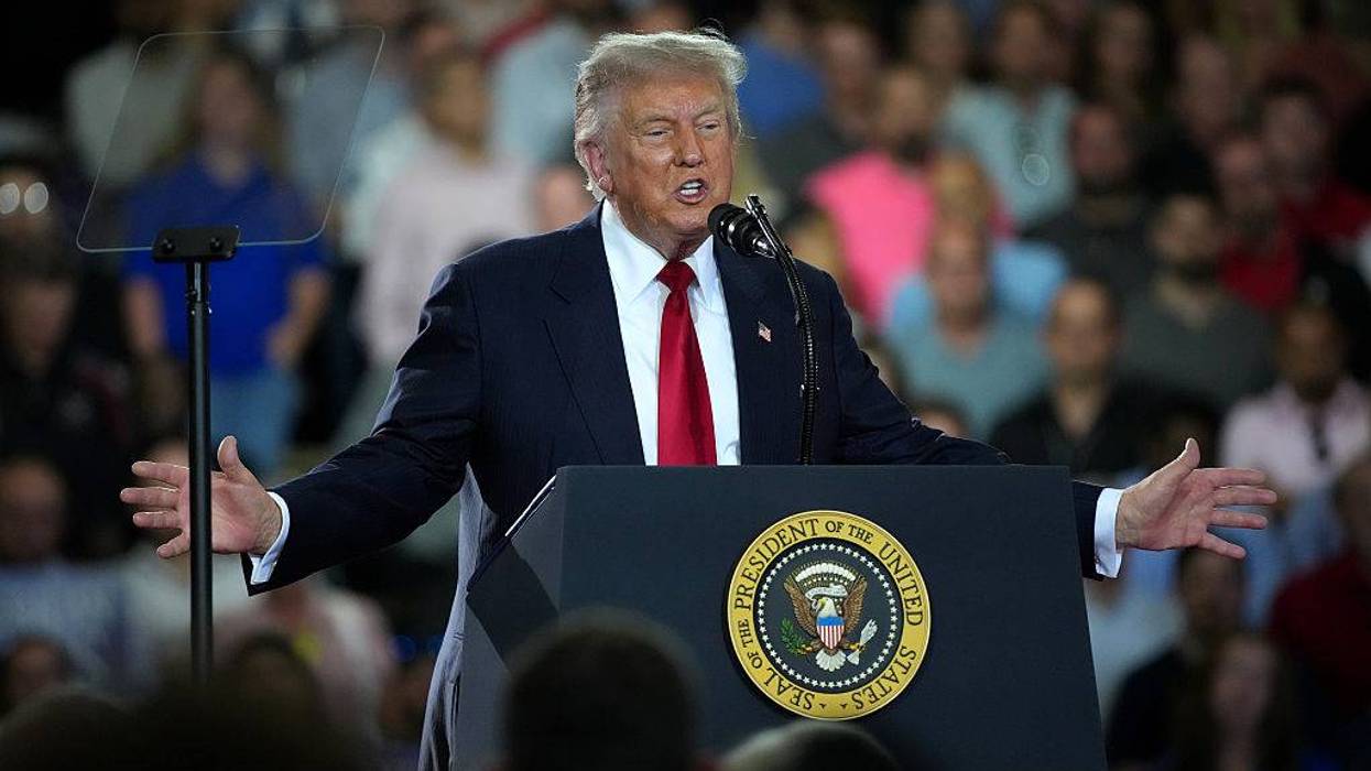 Donald Trump speaks at a podium with Presidential Seal, gesturing to a crowd.