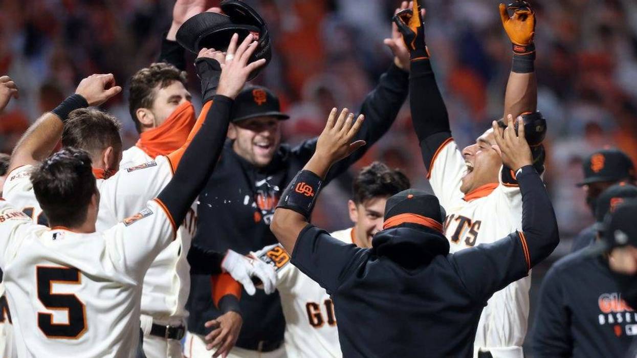Donovan Solano #7 of the San Francisco Giants is congratulated by teammates after he hit a walk off home run to win the game in the 11th inning against the Los Angeles Dodgers at Oracle Park on August 25, 2020 in San Francisco, California.