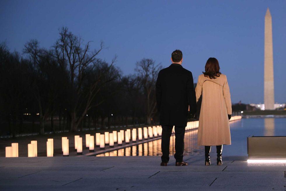 Douglas Emhoff (L) and U.S. Vice President-elect Kamala Harris look down the National Mall as lamps are lit to honor the nearly 400,000 American victims of the coronavirus pandemic at the Lincoln Memorial Reflecting Pool January 19, 2021 in Washington, DC.