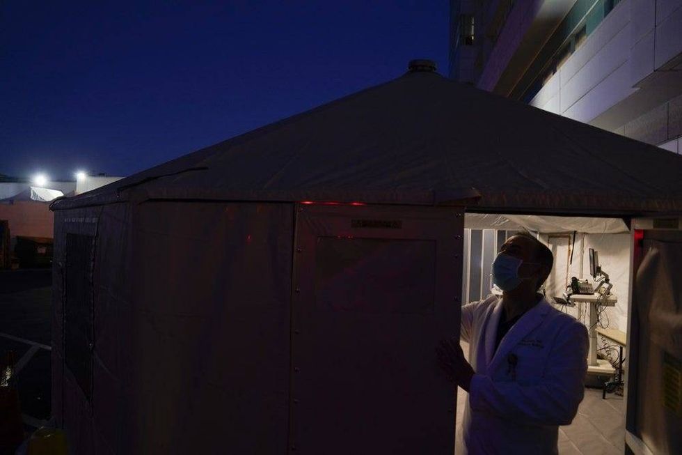 Dr. Jim Keany, an emergency medicine specialist, shuts the door of a triage tent set up to treat COVID-19 patients.