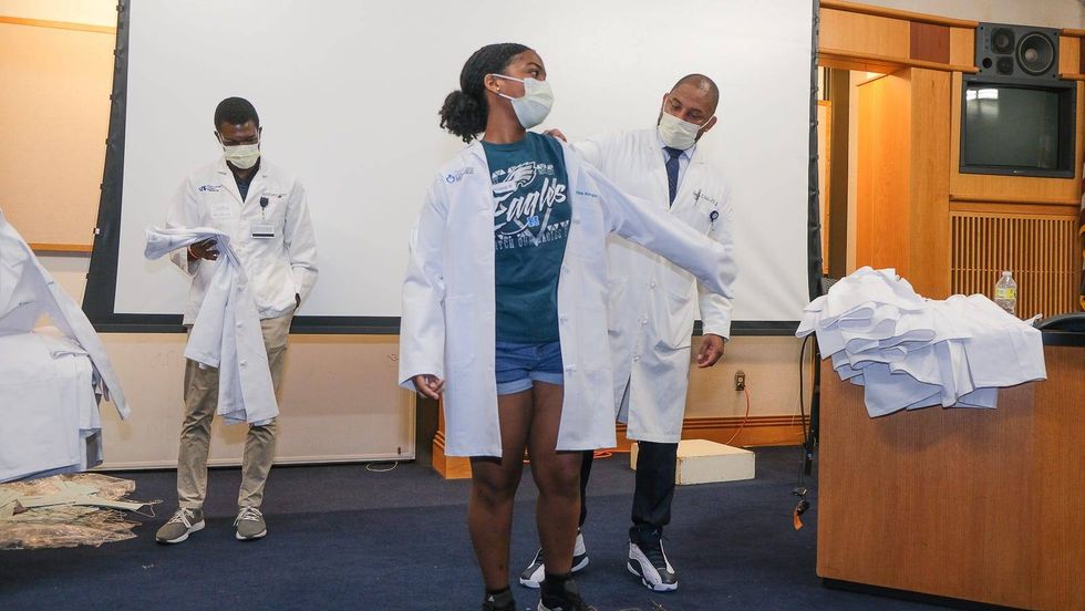 Dr. Thomas Butler calls students up one by one to adorned them with a brand new coat which they must wear throughout the week-long program.