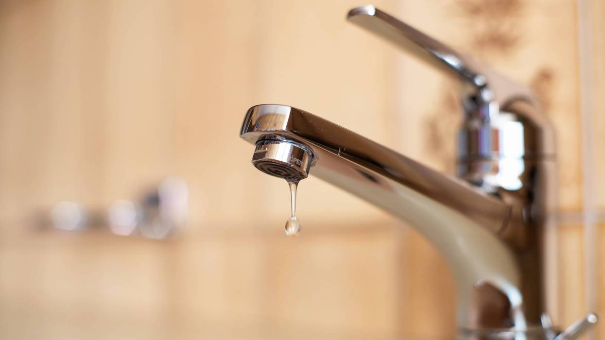 Dripping tap with inside apartment bathroom. Close up shot, shallow depth of field, no people