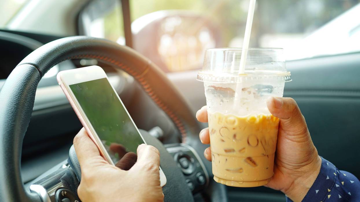 Driver texting and drinking iced coffee