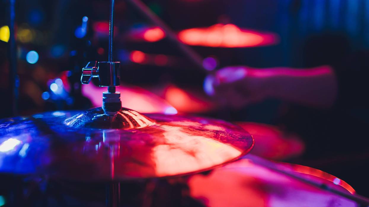 Drummer playing drum set at concert on stage. Music show. Bright scene lighting in club,drum sticks in hands