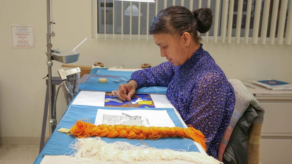 Duwenavue Sante Johnson stitches a battalion flag for the 224th Aviation Regiment of the U.S. Army National Guard.
