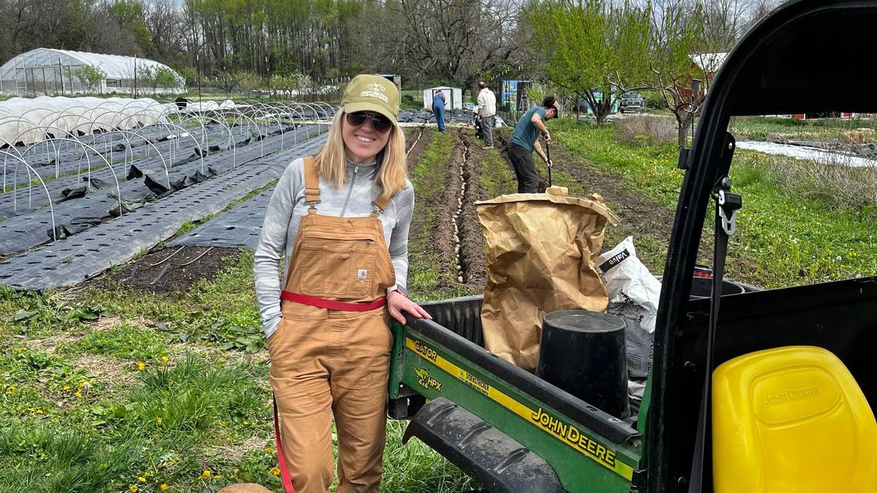 Earthdance founder Molly Rockamann and Ruby the Dog look on as potatoes are being planted on an April morning