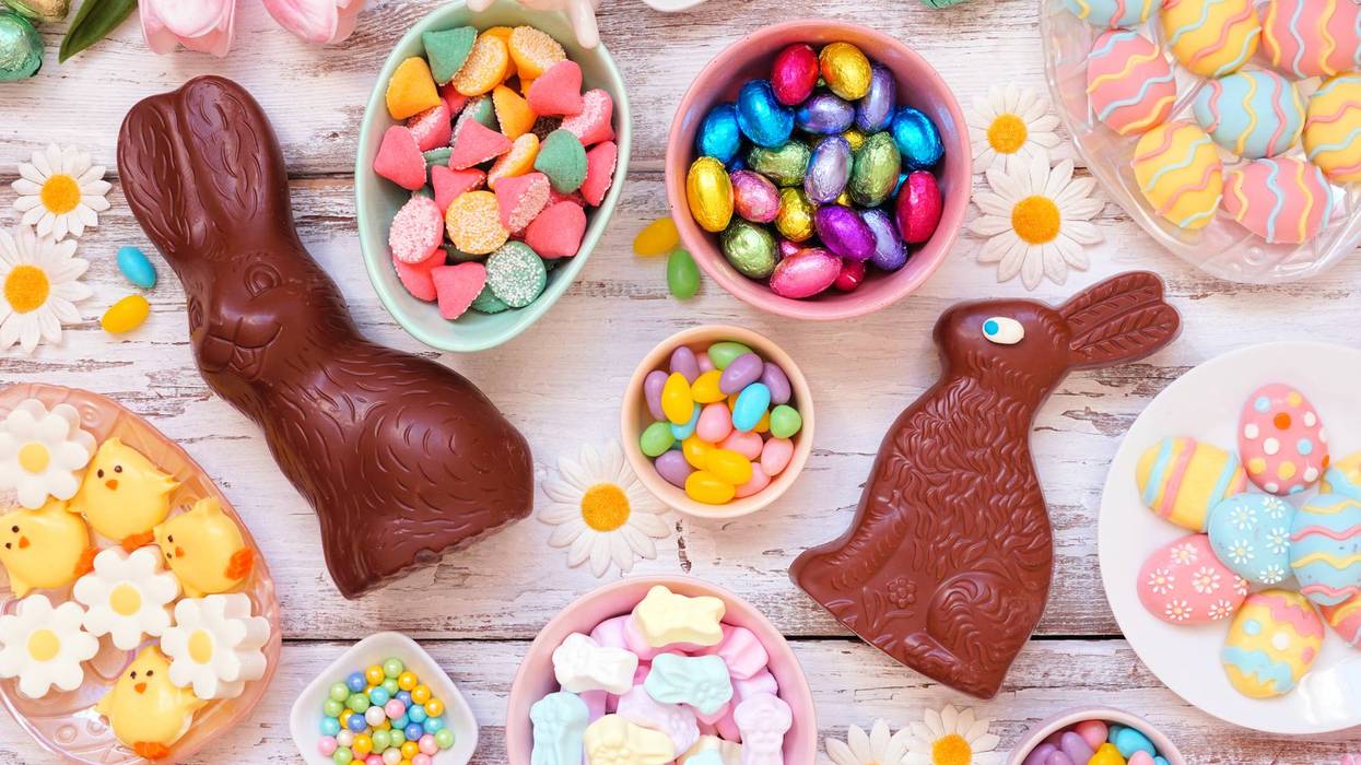 Easter candy table scene over a white wood background