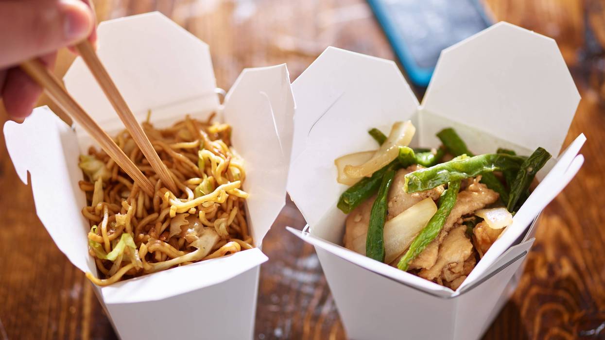 eating lo mein out of chinese take out box wih chopsticks