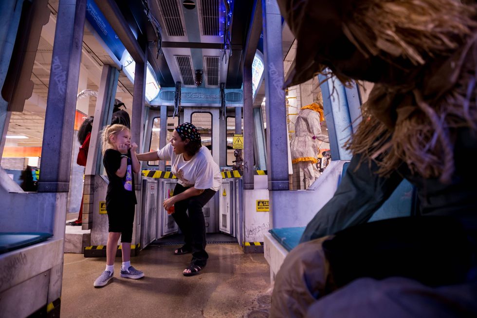 Ebone Gaston, who is celebrating her birthday, and her sister Olive Patterson react to an animatronic inside the subway scene for Spirit Halloween