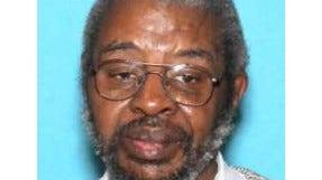 Elderly Black man with grey hair and beard, wire-rimmed glasses and sweater