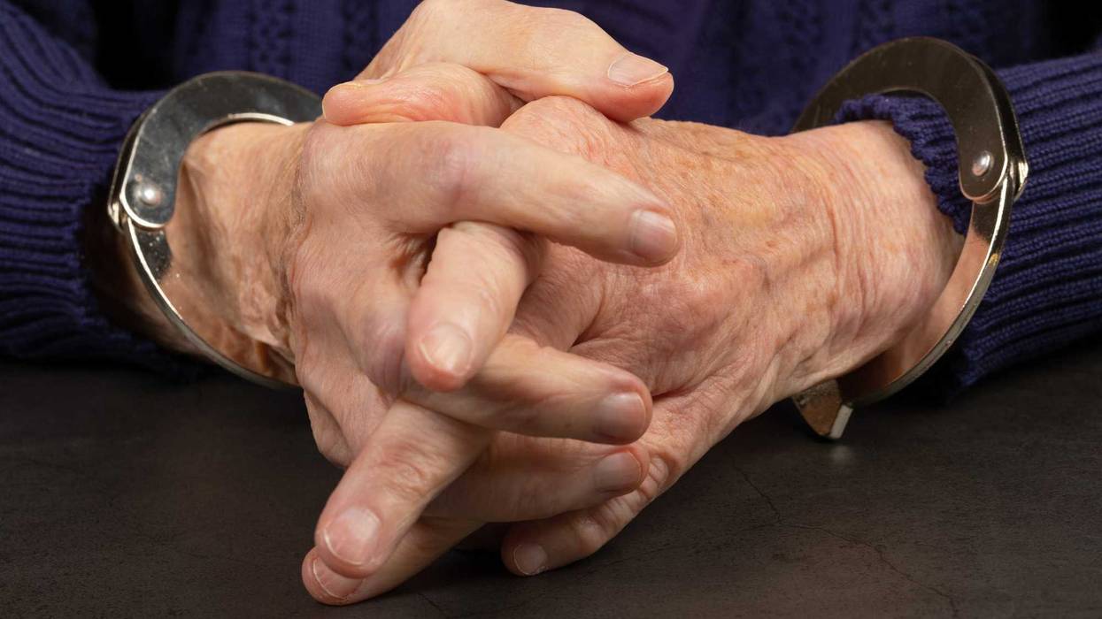 Elderly person in handcuffs.