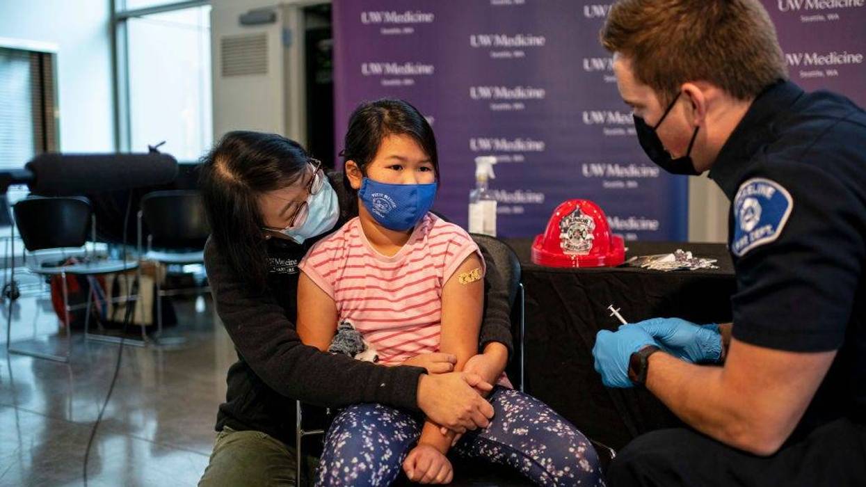 Elise Wong, 7, sits in the lap of her mother, Crystal Wong, after receiving a Pfizer-BioNtech Covid-19 vaccine from firefighter Luke Lindgren on November 3, 2021 in Shoreline, Washington.