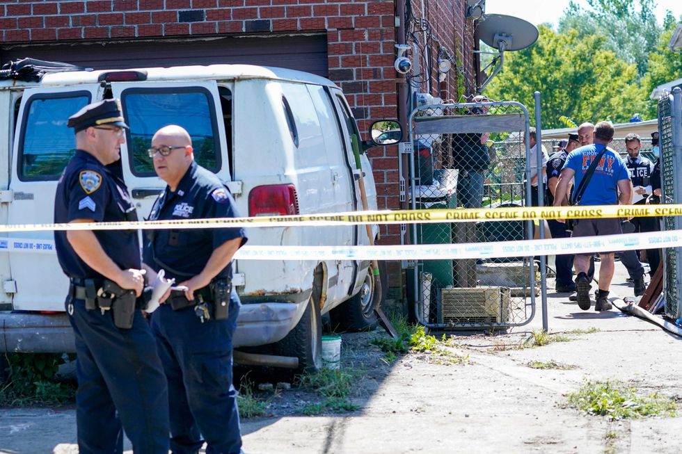 Emergency service personnel work at the scene of a basement apartment where bodies were found on Peck Ave. in the Flushing neighborhood of the Queens