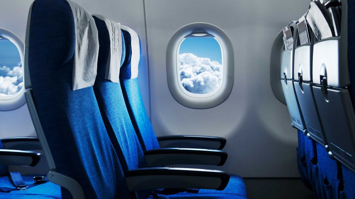 Empty air plane seats. Blue sky and clouds in the window. Airplane interior
