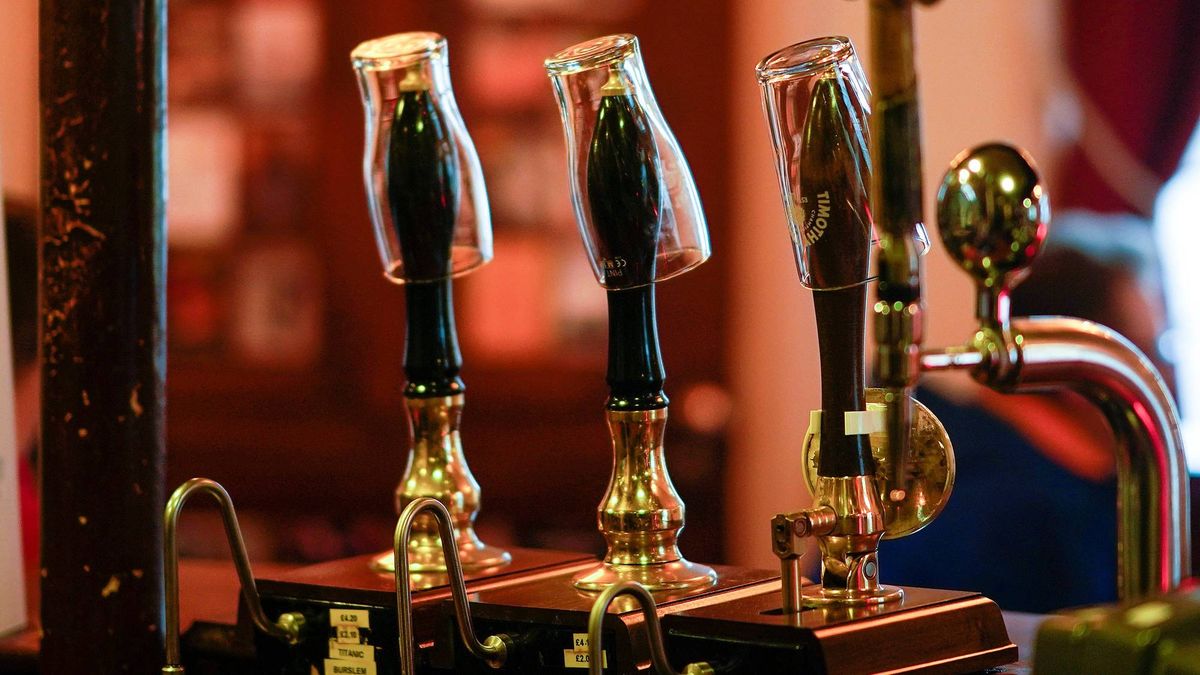 Empty pint glasses sit on the top of beer pumps of the Peveril Of The Peak pub,